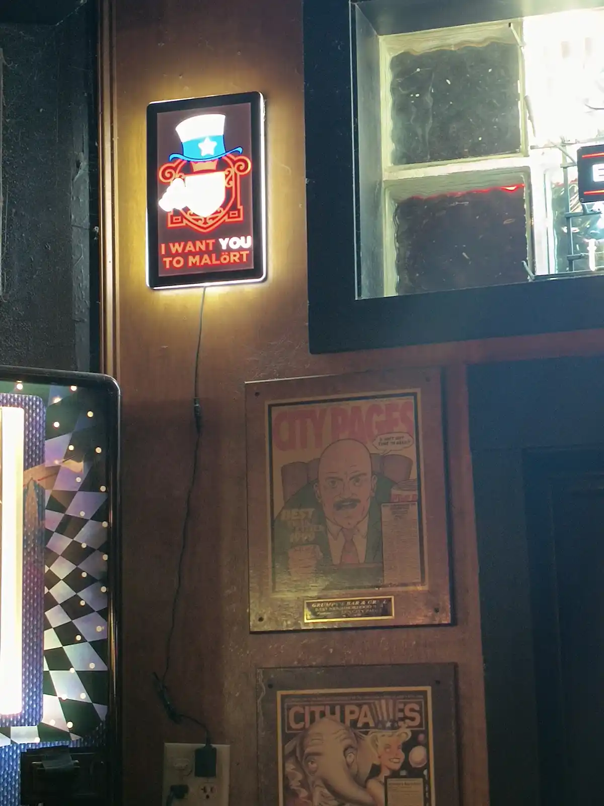 A lit neon sign on a wooden wall features a cartoon Uncle Sam figure in a top hat pointing forward, with the text 'I WANT…
