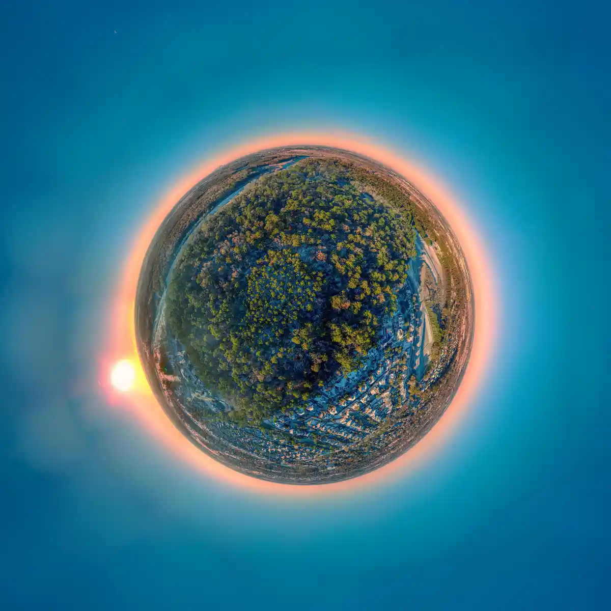 A 360-degree spherical panorama of a forested and suburban landscape, with the sun visible on the left and a crescent moon…