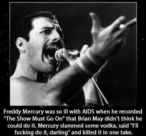 A black and white photo of Freddie Mercury singing passionately into a microphone, his mouth wide open and one hand raised…