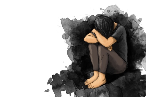 An illustrated person with dark hair sits curled up, head buried in knees, surrounded by black ink splatters on a white…
