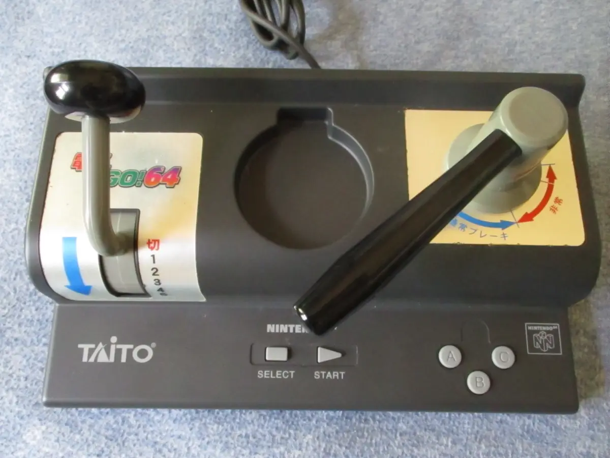 A black Nintendo 64 controller modified with two large, mismatched joysticks, one black and one grey, with Japanese text…