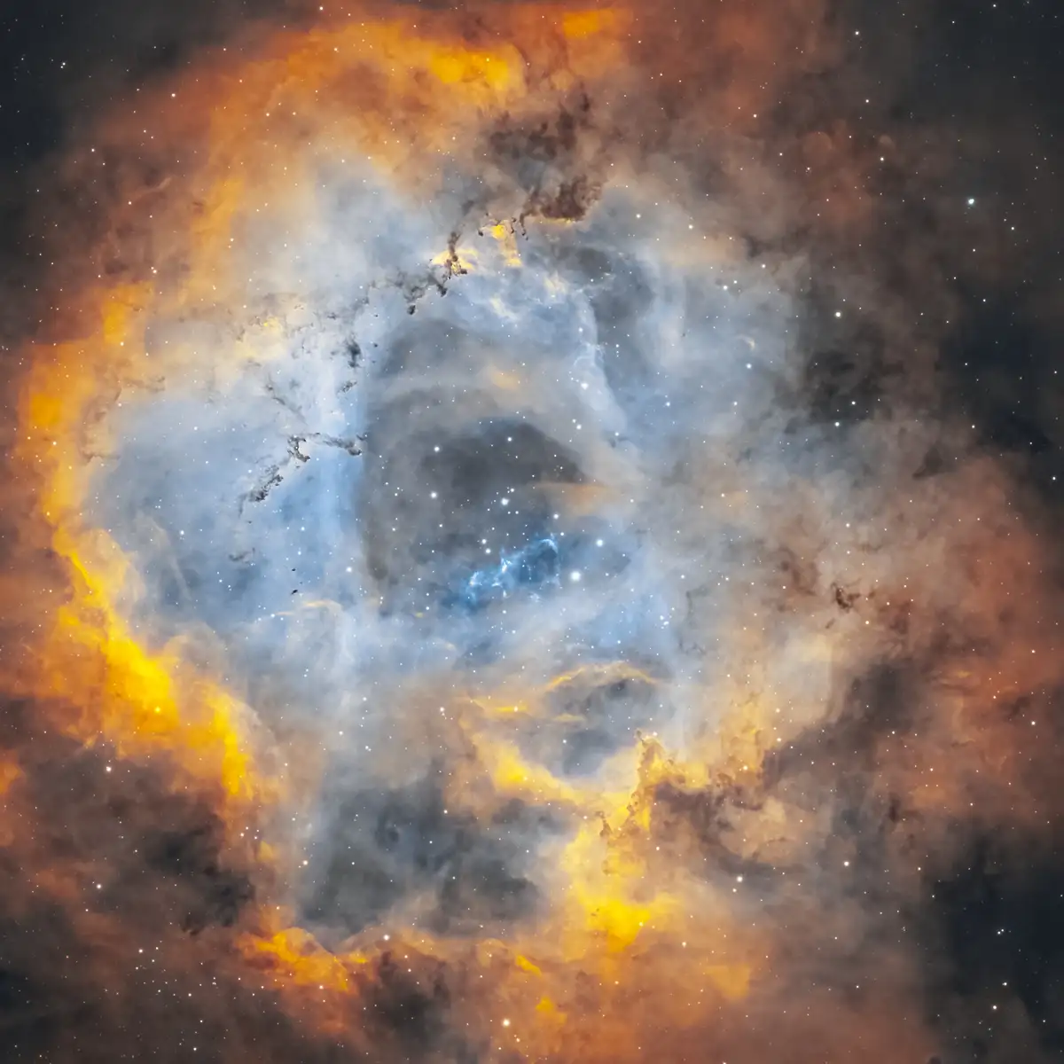 A vibrant space nebula image with swirling orange, yellow, and blue clouds of gas and dust, dotted with countless stars…