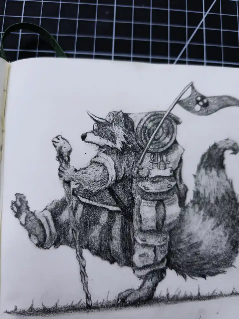 A pencil sketch in a sketchbook depicts a raccoon dressed in armor, holding a bone as a weapon and a flag with a raccoon…