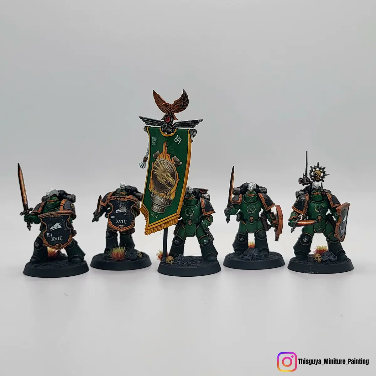 Five intricately painted Warhammer 40,000 Space Marine miniatures, identified as the XVIIIth Legion (Iron Hands), stand in a…