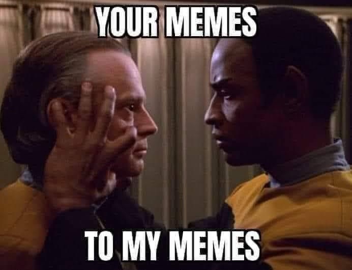 Two men in Star Trek uniforms face each other, one with his hand on the other's cheek in a confrontational pose. The text…