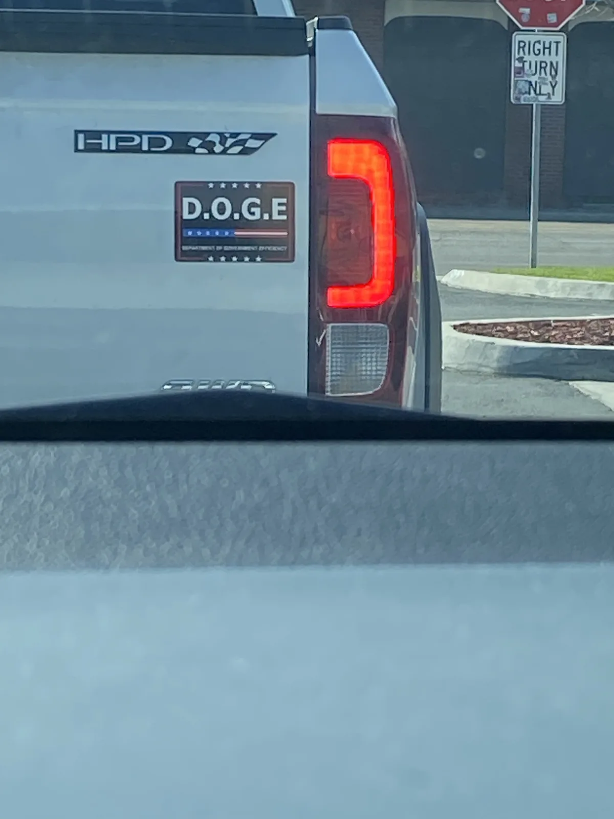 A white pickup truck with an 'HPD' badge and a 'D.O.G.E. DEPARTMENT OF GOVERNMENT EFFICIENCY' sticker on its tailgate is…