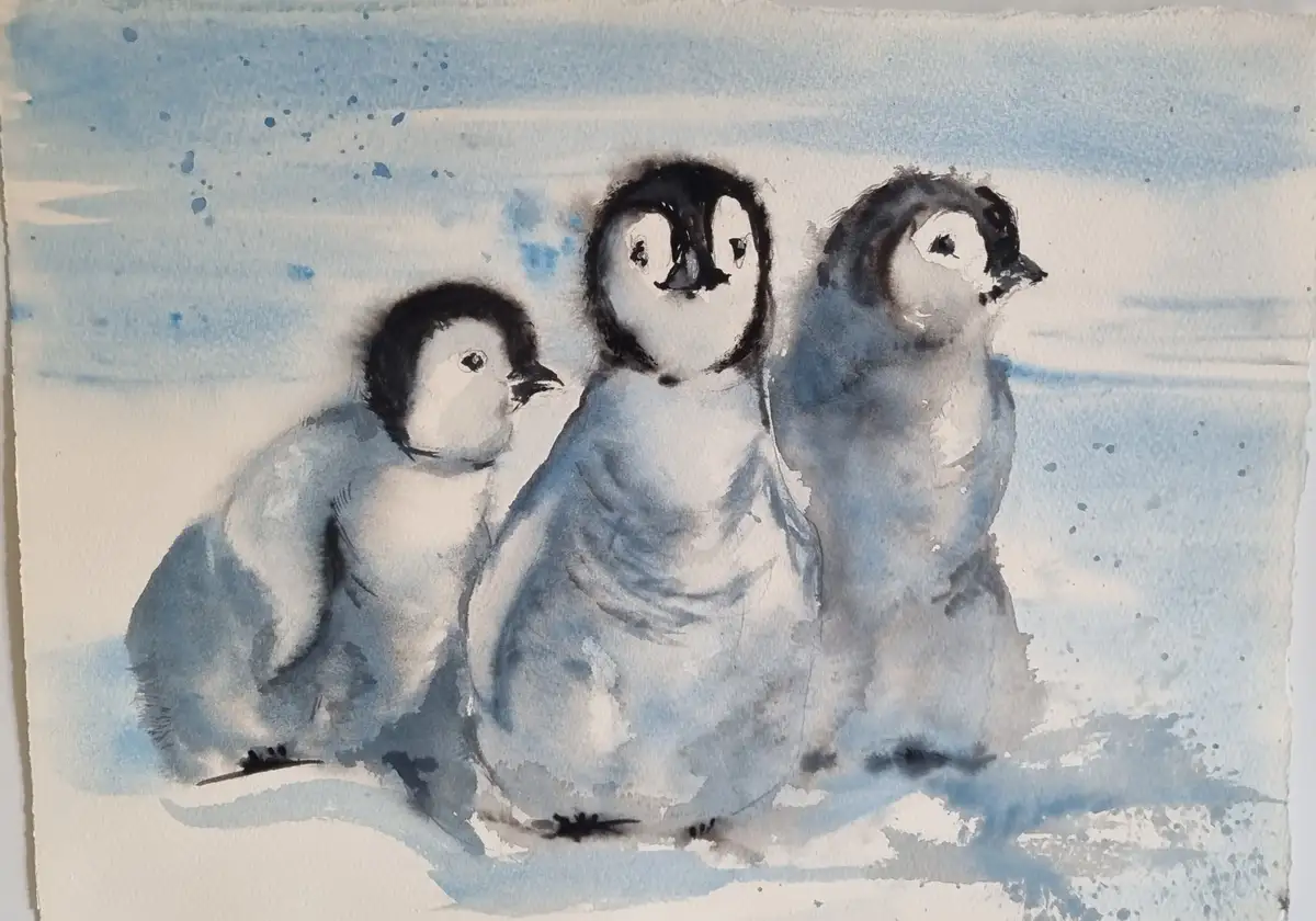 A watercolor painting shows three baby penguins standing together on snowy ground, rendered in soft blues and whites with…