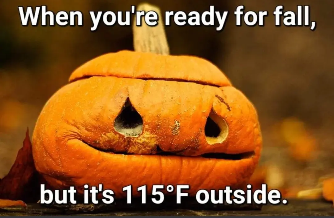A close-up photo of a carved orange pumpkin with a sad, downturned mouth and triangular eyes, sitting on a surface with…