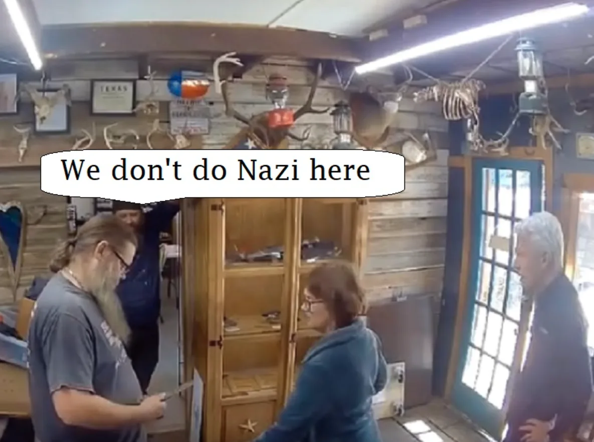 In a rustic shop decorated with deer antlers, animal skulls, and a Texas flag, three people are present. A man in a grey…