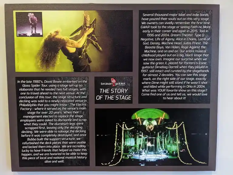 A museum-style plaque titled 'THE STORY OF THE STAGE' by Broken Goblet Brewing details the history of a concert stage. It…