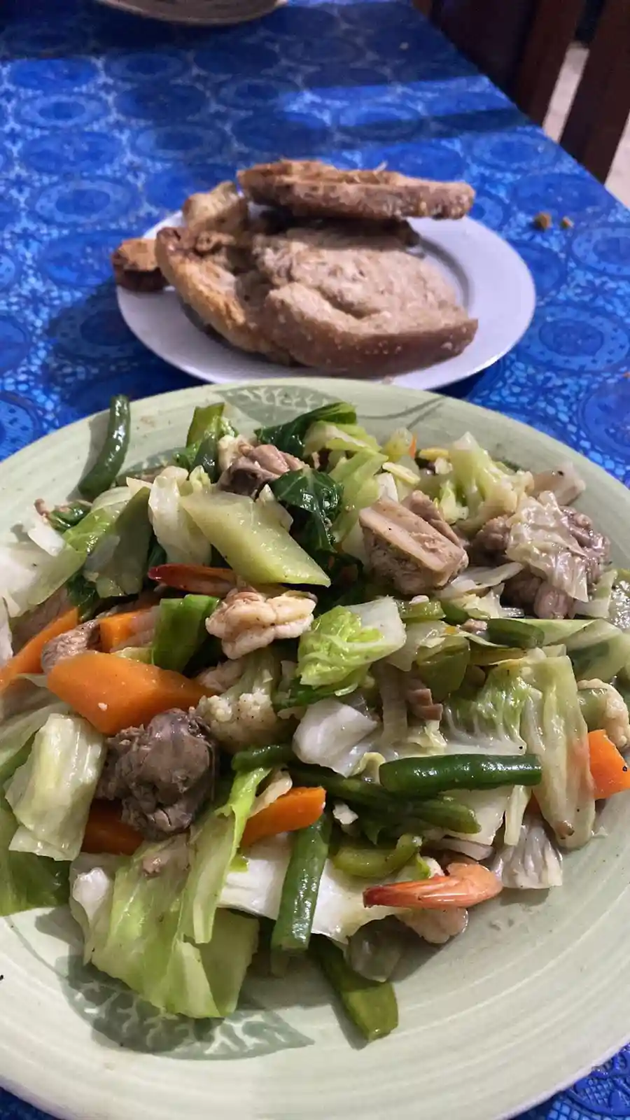 A close-up photo shows a plate of mixed vegetables including cabbage, carrots, green beans, and shrimp, mixed with pieces of…