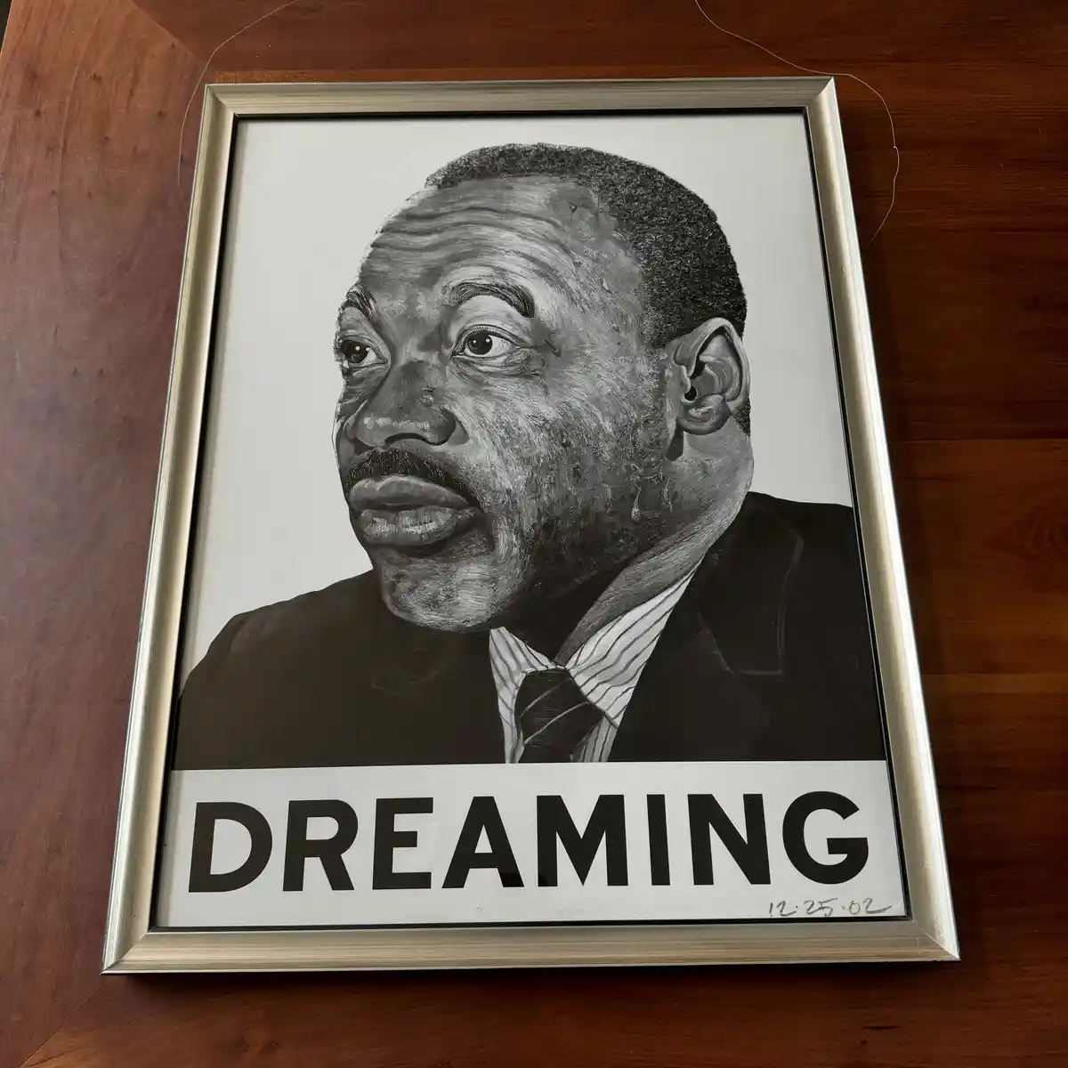 A framed black-and-white portrait of Martin Luther King Jr. shows him with tears streaming down his face, overlaid with the…