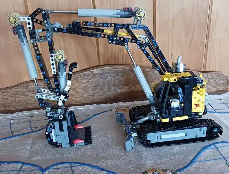 A detailed LEGO Technic model of an excavator with a yellow cab, black tracks, and articulated arms, positioned on a…