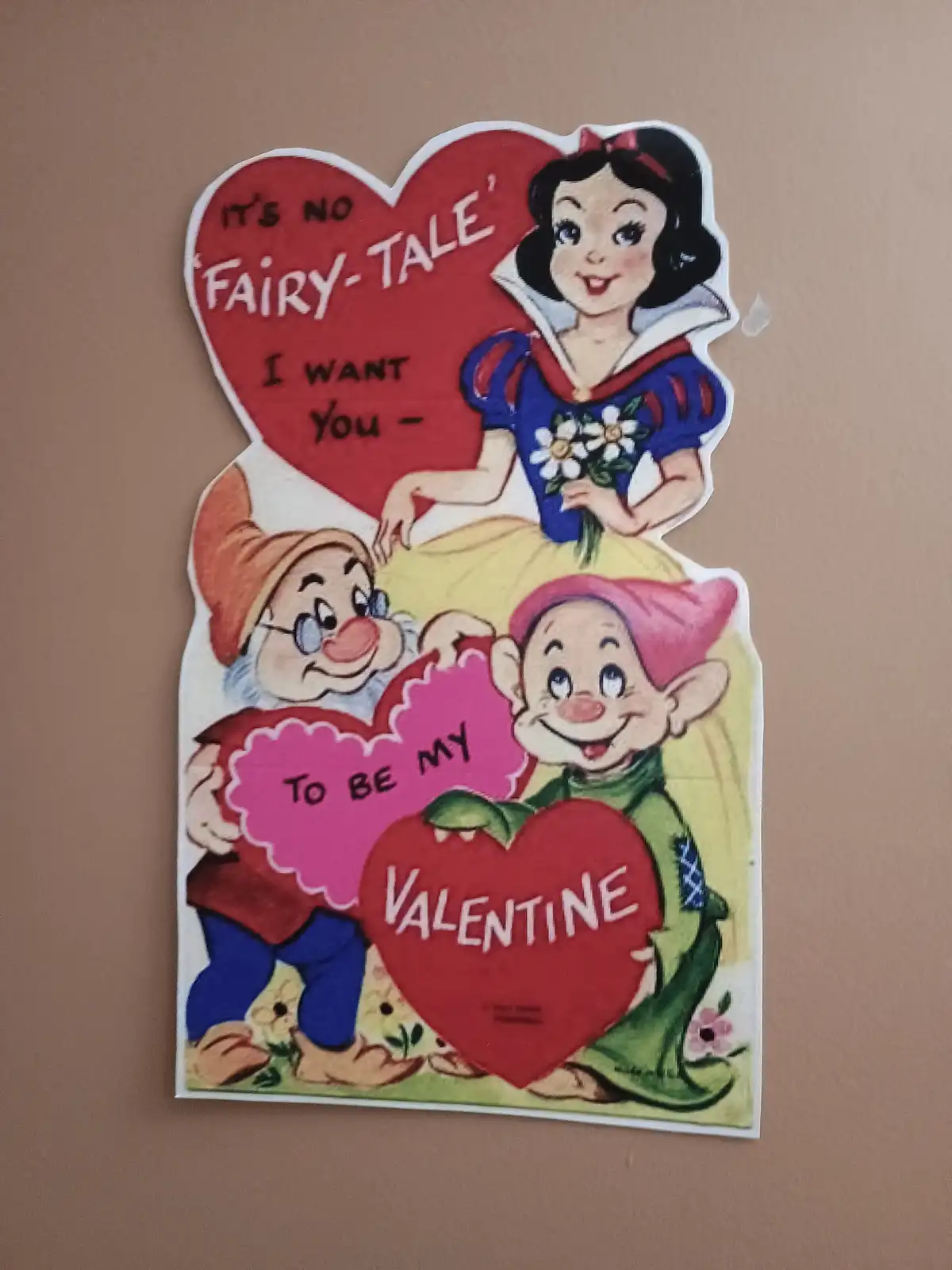 A vintage-style Valentine's Day card features Snow White holding a red heart that reads 'IT'S NO 'FAIRY-TALE' I WANT YOU -'…