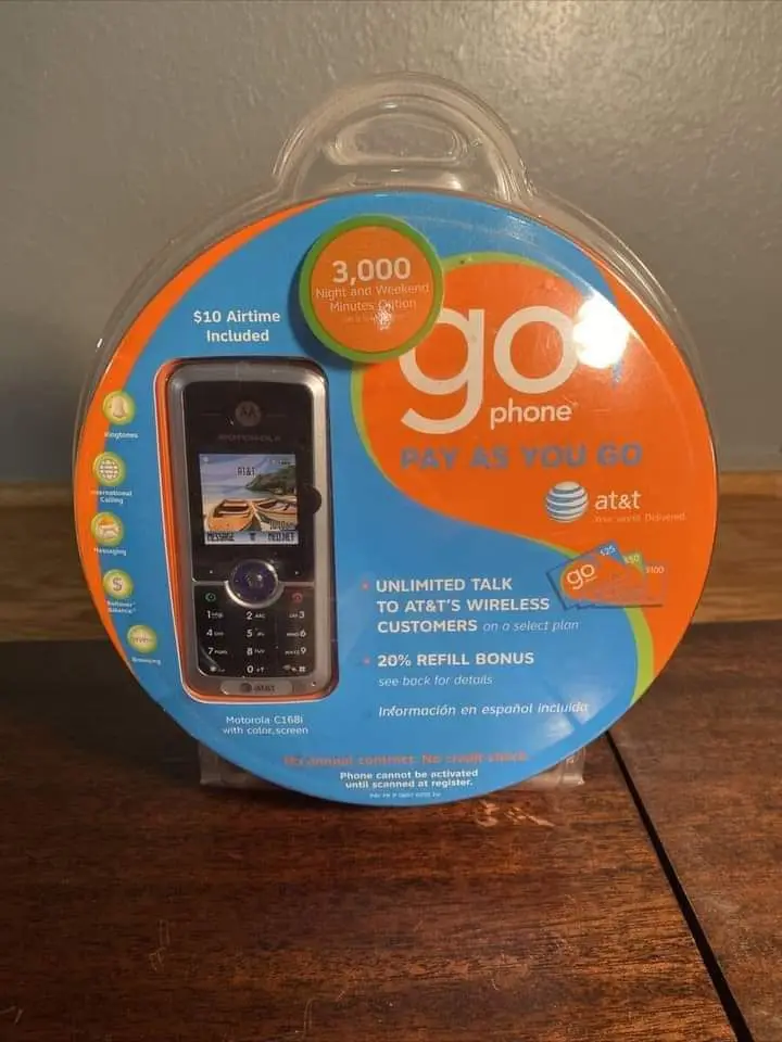 A vintage AT&T Go Phone in its original circular plastic packaging, featuring a Motorola C168i with color screen. The…