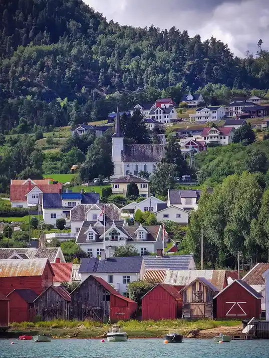 A scenic photo of a Norwegian village with colorful houses, a church, and boats on the water, overlaid with the text 'i'm…