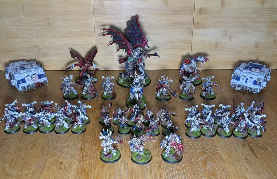 A collection of intricately painted miniature figurines, mostly white-armored warriors with red and blue accents, arranged…