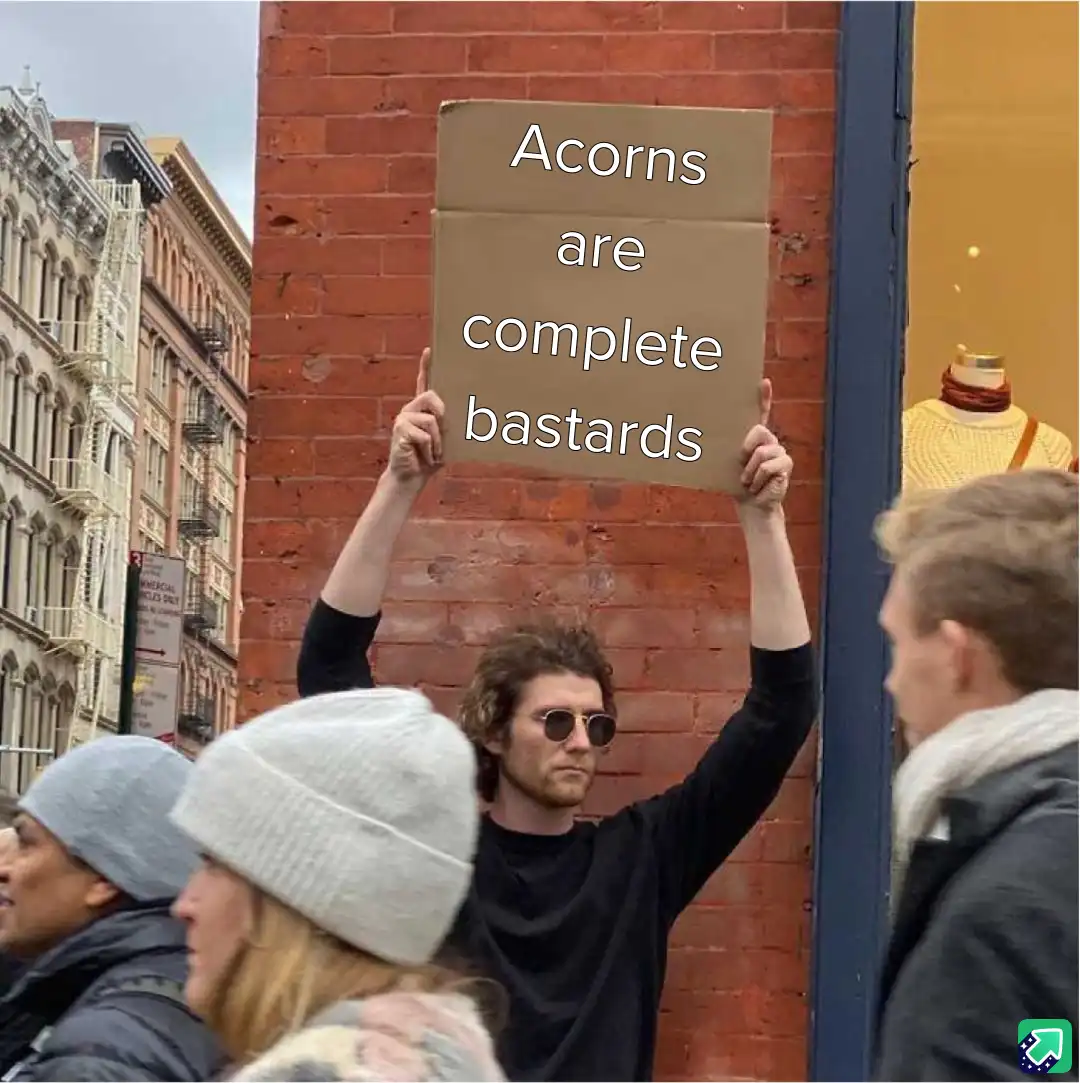 A man with curly hair and sunglasses holds up a cardboard sign that reads 'Acorns are complete bastards' while standing on a…