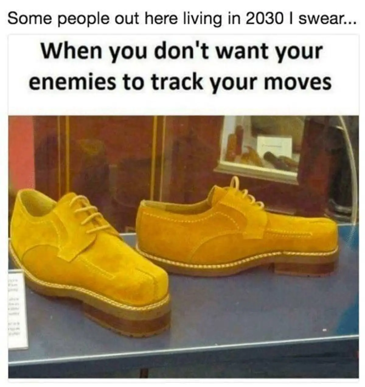 A pair of bright yellow suede shoes with thick soles are displayed on a blue shelf inside a glass case, likely in a museum…