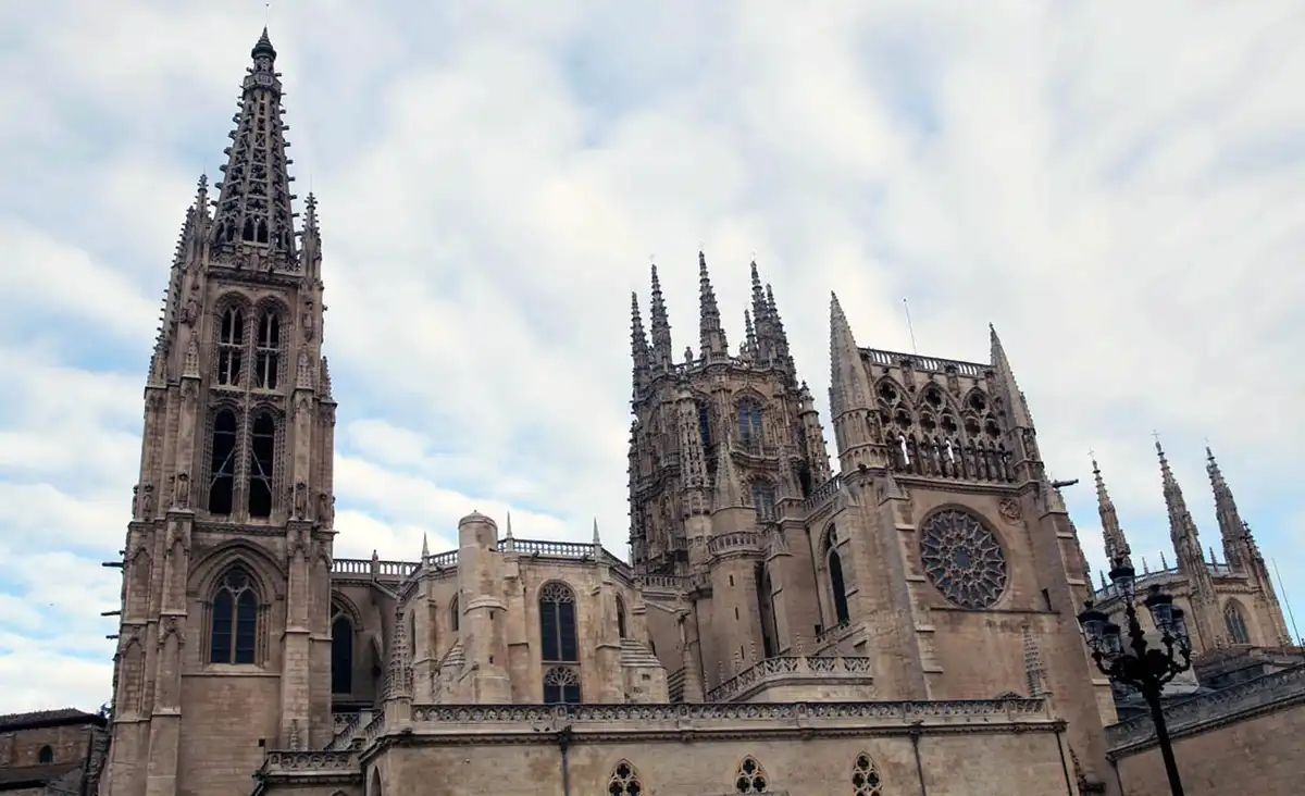 a low-angle photograph of the ornate, stone gothic cathedral of leon, featuring its tall spires, intricate facade, and a…