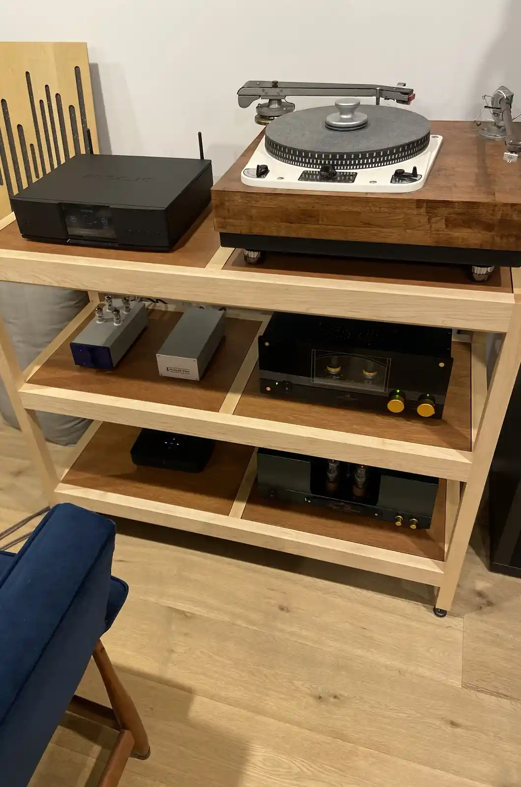A high-end audio setup featuring a turntable on a wooden shelf unit, surrounded by various amplifiers, preamps, and other…