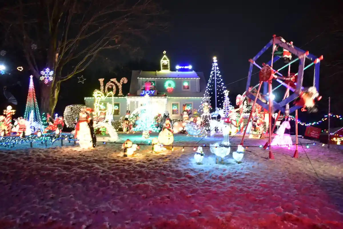 A house is extravagantly decorated with Christmas lights and inflatable figures at night, featuring large illuminated…