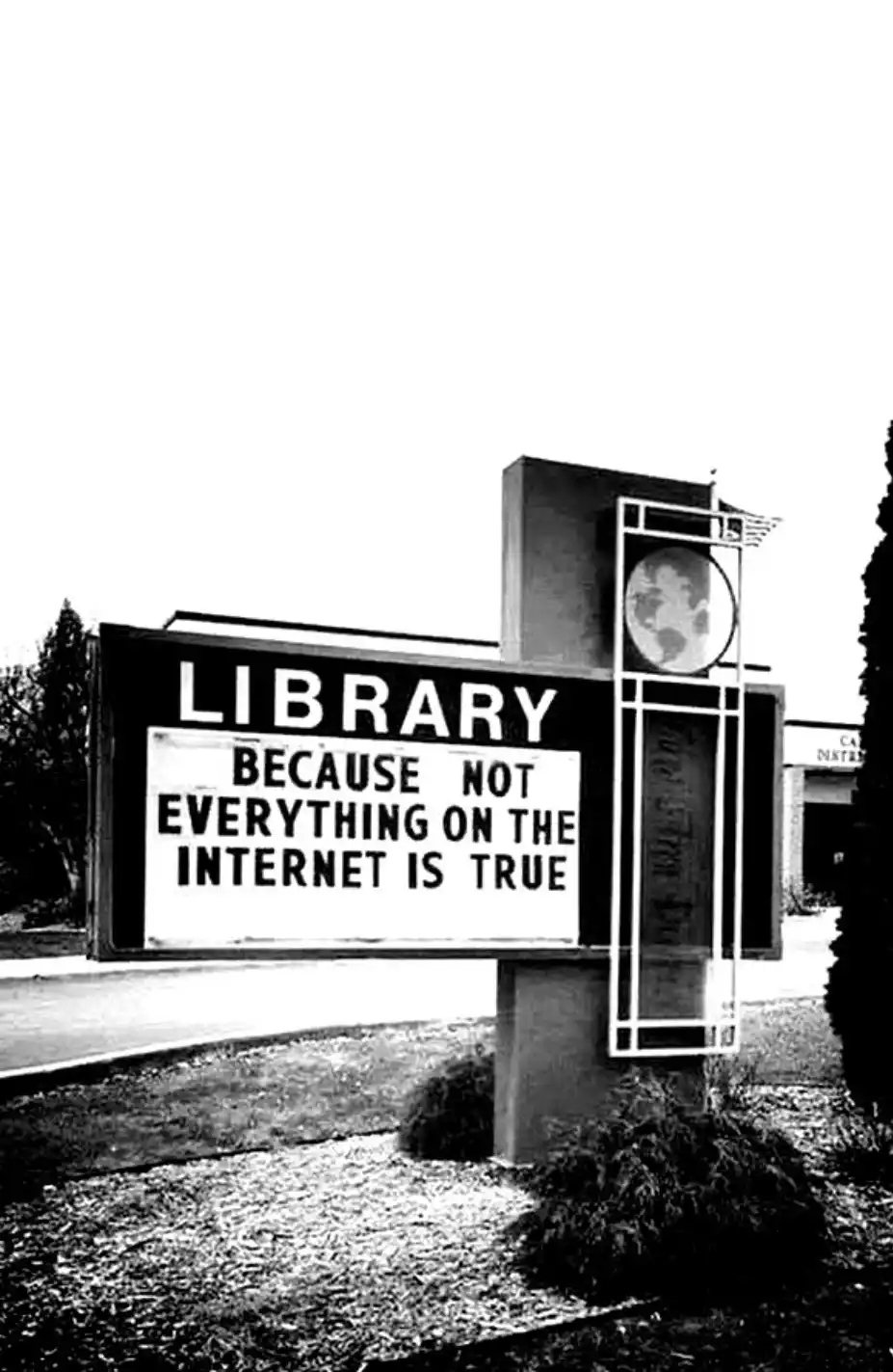 A black-and-white photo of a library sign with a marquee that reads 'LIBRARY BECAUSE NOT EVERYTHING ON THE INTERNET IS…