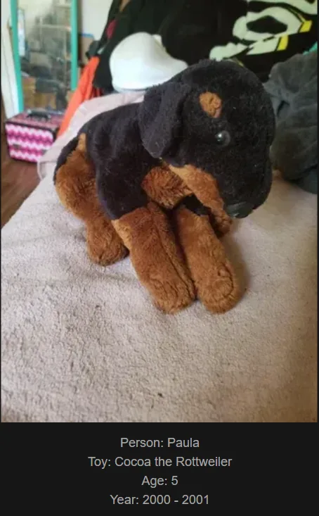A black and tan plush Rottweiler toy named Cocoa sits on a beige carpet, with text overlay identifying it as belonging to…