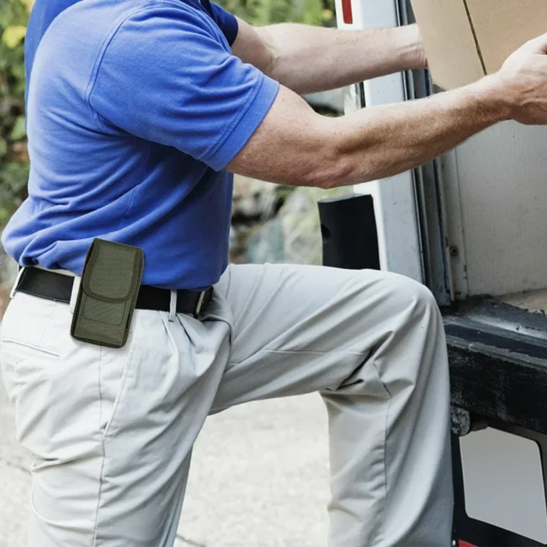 a man in a blue shirt and khaki pants is leaning against a truck while loading a box, with a small green pouch attached to…