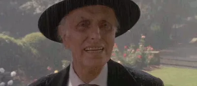 A sequence of six frames shows an elderly man in a black hat and suit standing in the rain, his expression shifting from a…
