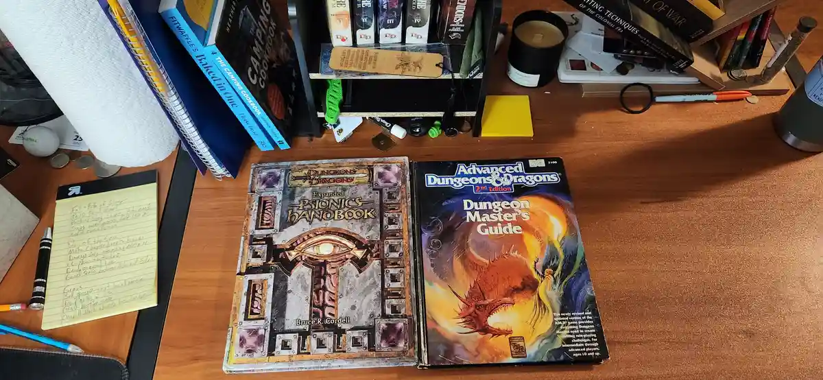 Two Dungeons & Dragons books sit open on a cluttered wooden desk: 'Expanded Psionics Handbook' and 'Advanced Dungeons &…