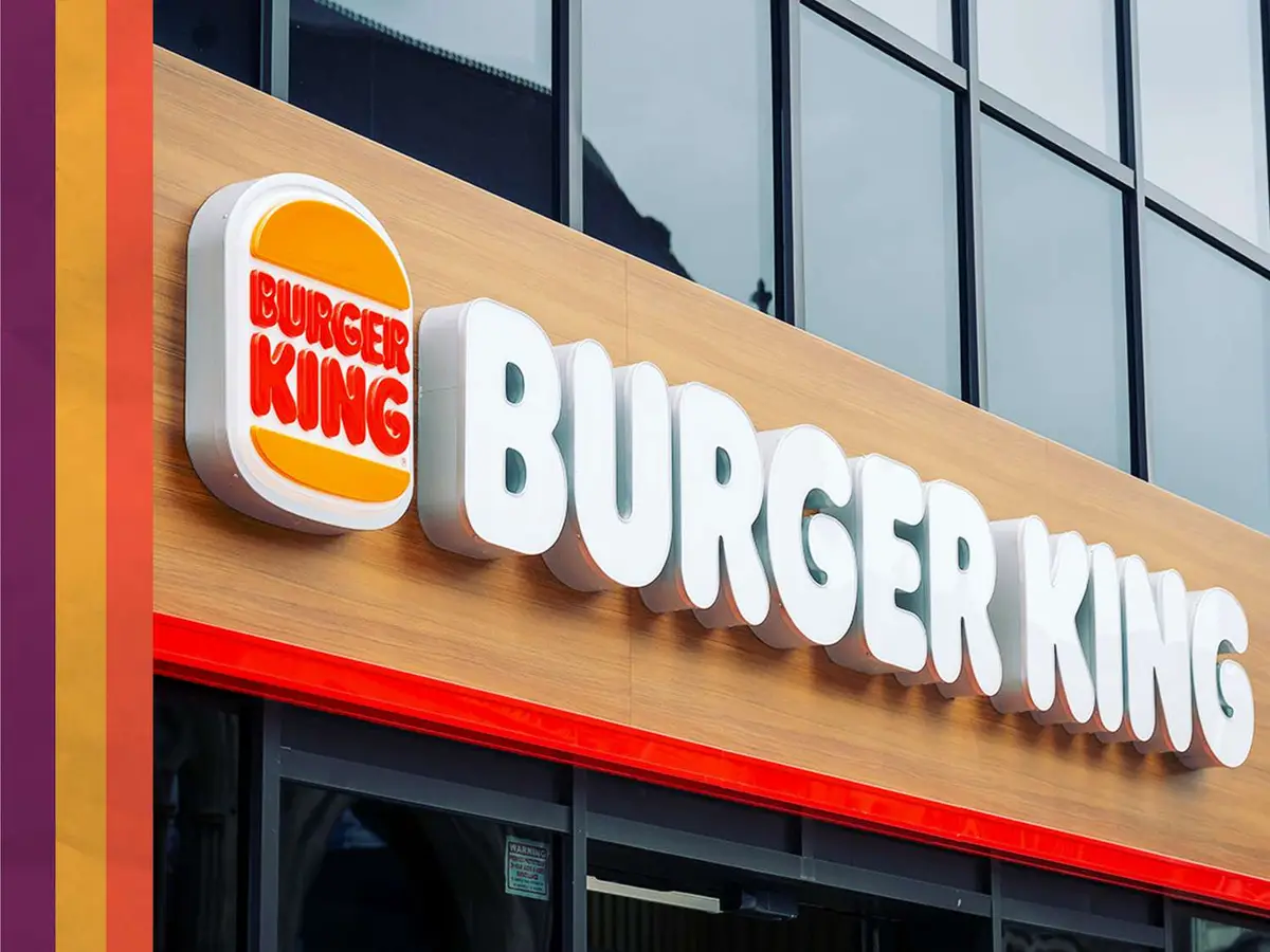 A close-up photograph of a Burger King restaurant sign, featuring the iconic logo with red text on a yellow burger bun…