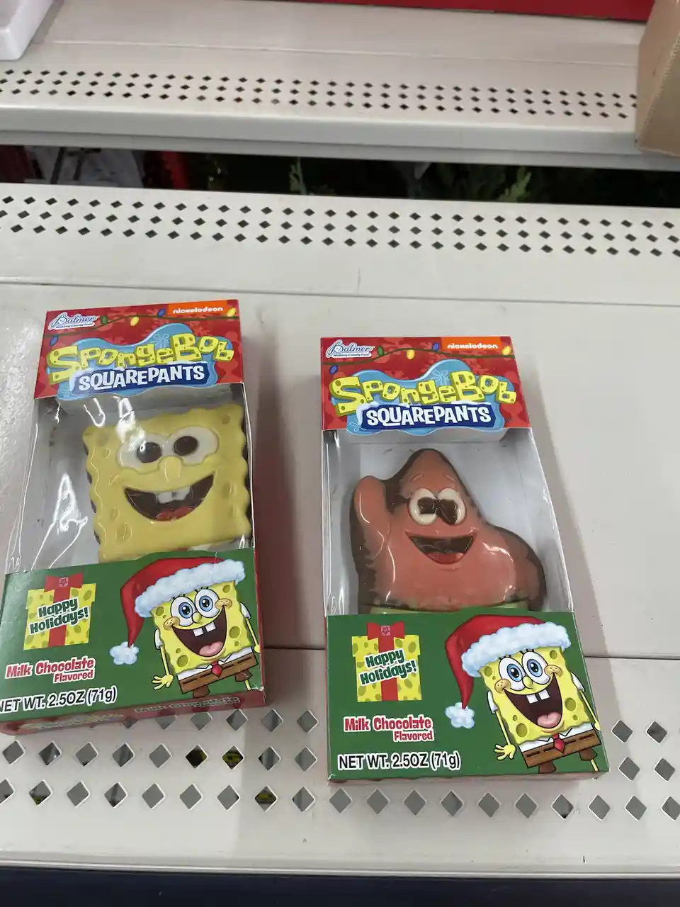 Two holiday-themed SpongeBob SquarePants chocolate bars sit side-by-side on a store shelf. The left package contains a…
