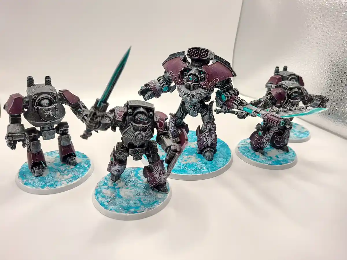 Four intricately painted, heavily armored robotic warrior miniatures stand on circular bases with blue and white textured…