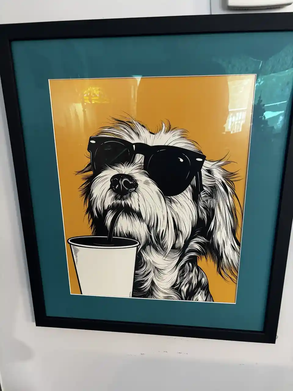 A framed art print shows a stylized black-and-white illustration of a fluffy white dog wearing large black sunglasses and…