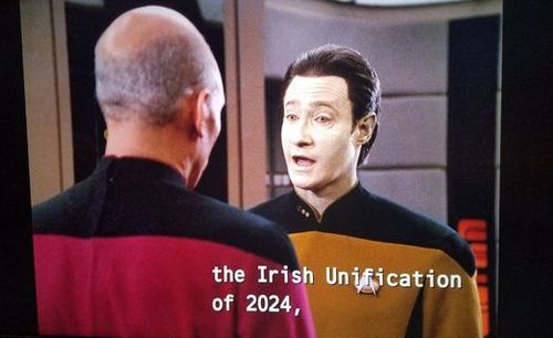 A still from Star Trek: The Next Generation shows Captain Jean-Luc Picard facing a bald man in a red and black uniform…