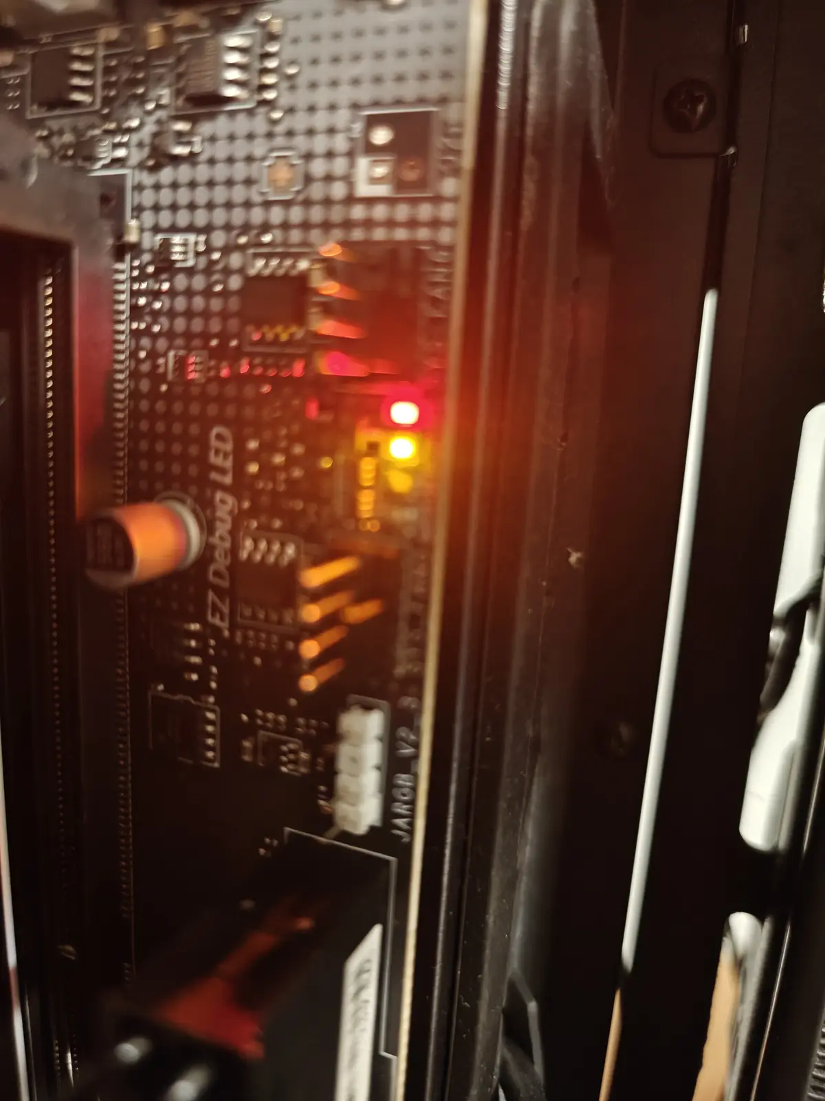 A close-up photo of a computer motherboard's debug LED section, showing a red light illuminated and a yellow light lit up…