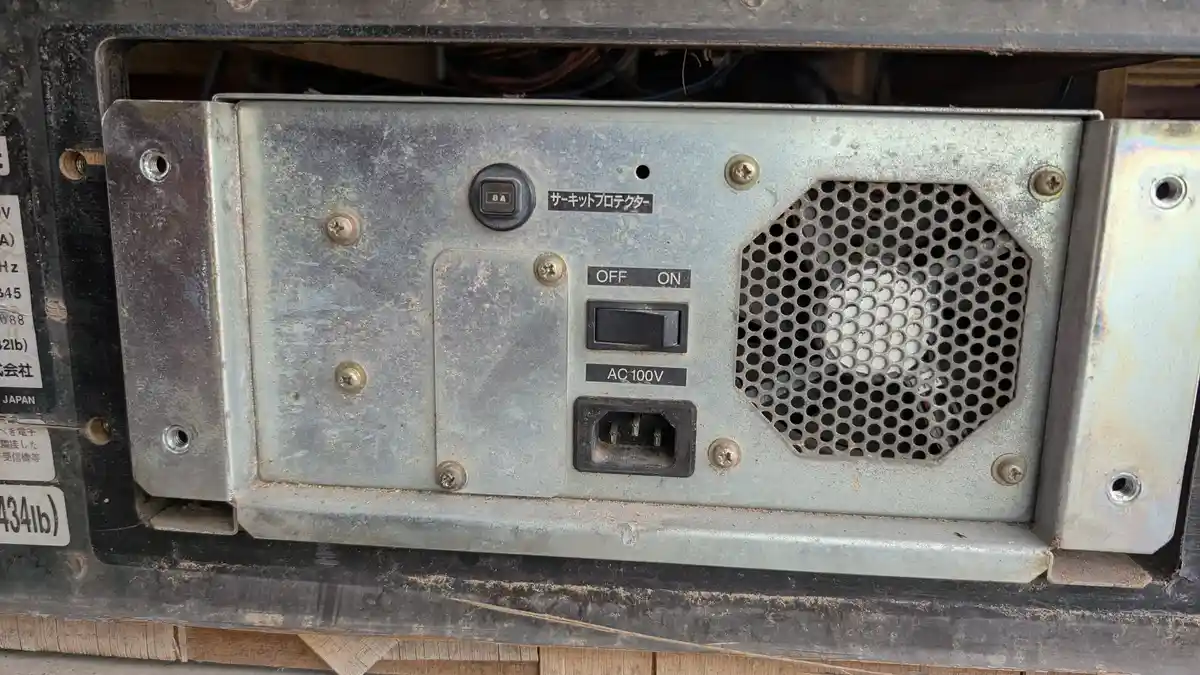 A close-up of a dusty, weathered Japanese electronic device's power panel showing an 'OFF ON' toggle switch, an 'AC 100V'…