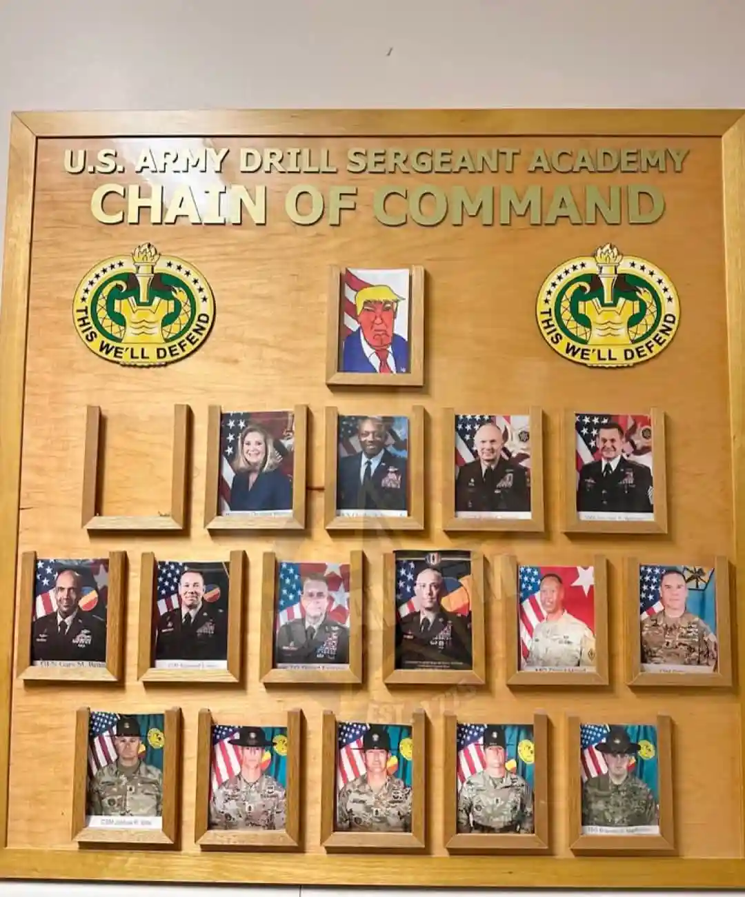 A wooden display board labeled 'U.S. ARMY DRILL SERGEANT ACADEMY CHAIN OF COMMAND' shows a hierarchical arrangement of…