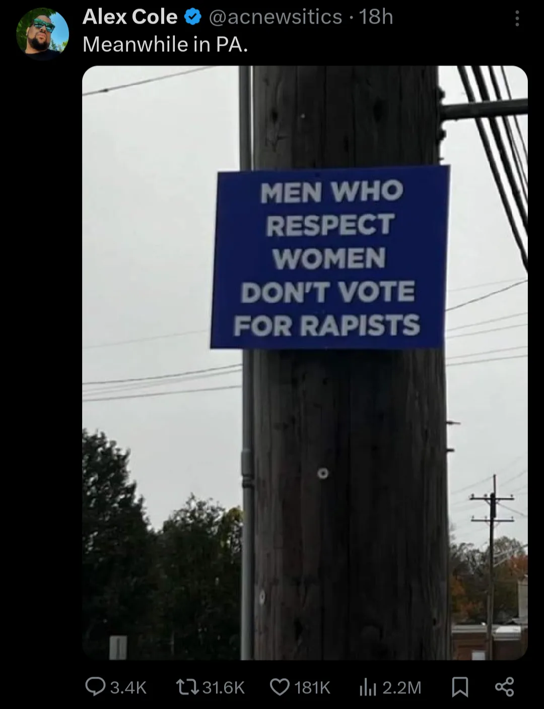 A blue sign with white text reading 'MEN WHO RESPECT WOMEN DON'T VOTE FOR RAPISTS' is taped to a wooden utility pole…