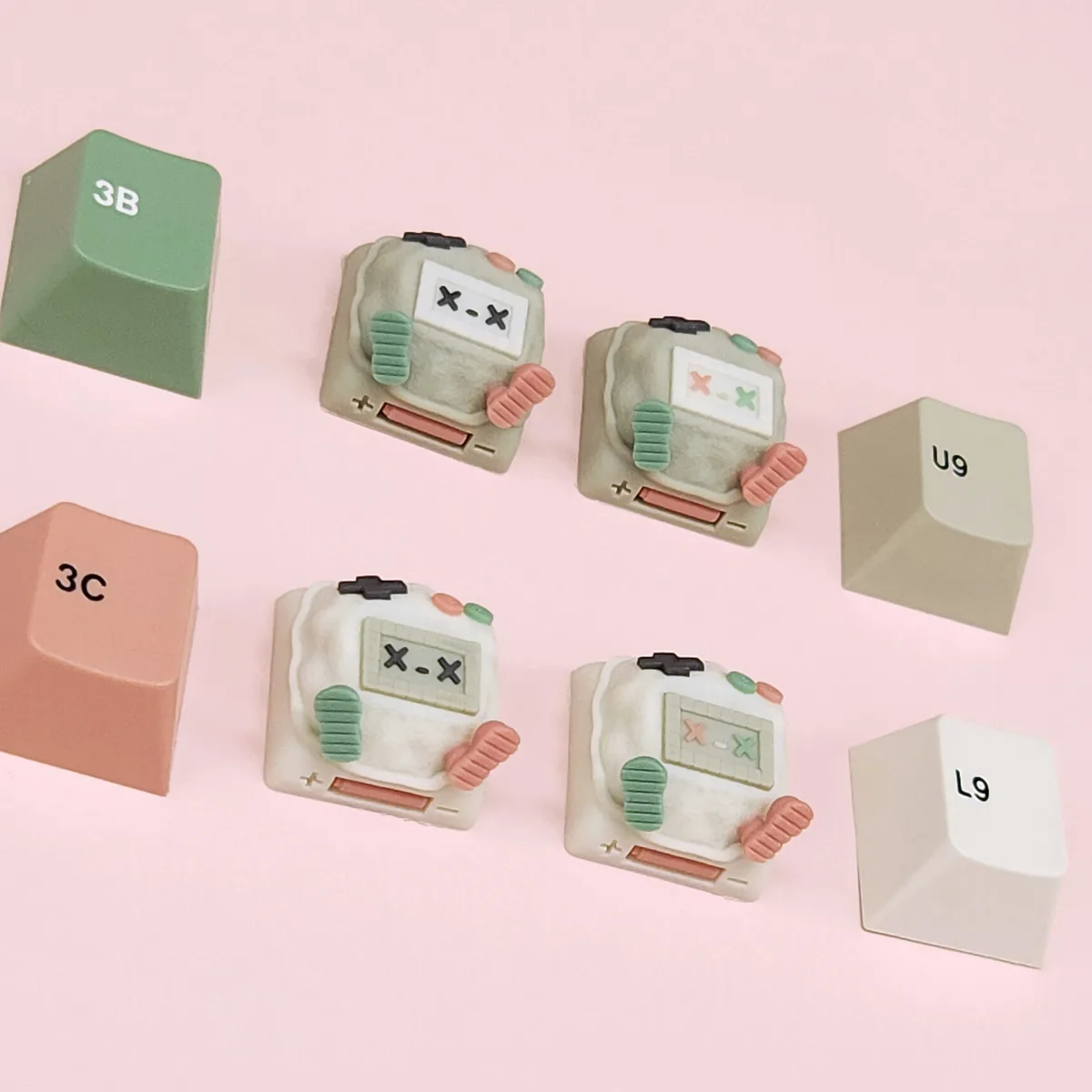 The image displays four small, cute, robot-shaped keyboard keycaps with X-X faces, arranged on a pink background alongside…