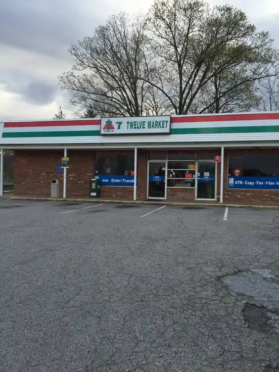 An exterior shot of a convenience store with a sign that reads '7 TWELVE MARKET', mimicking the 7-Eleven logo but with '7'…