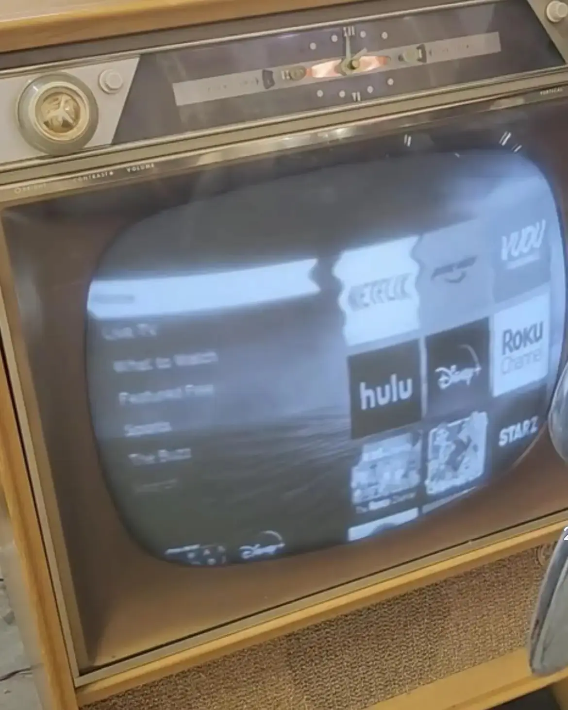 An old-fashioned, wood-framed television with a curved screen displays a modern streaming service interface featuring logos…