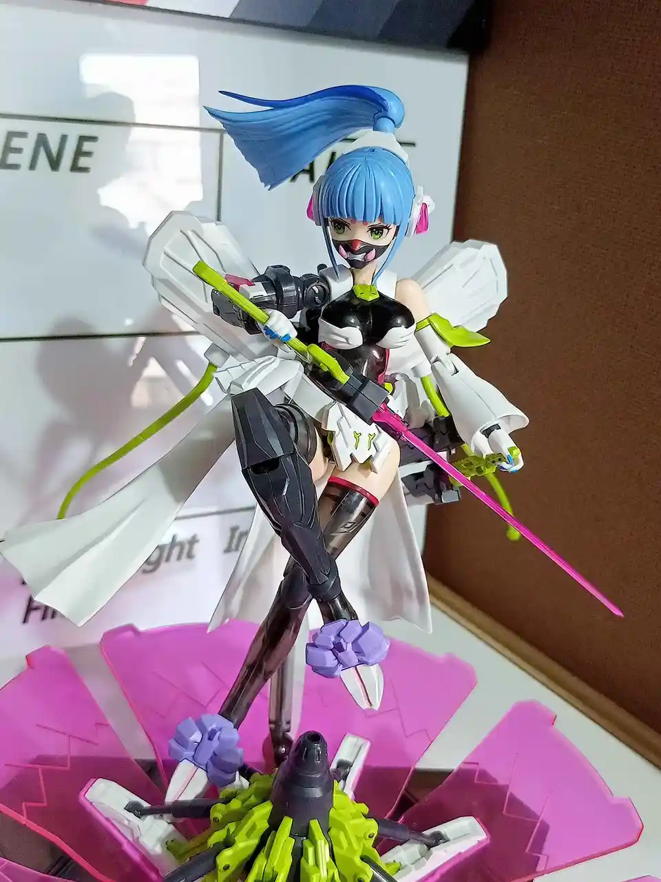 A plastic anime-style action figure of a female character with blue hair, green eyes, and a black mask, holding a large…
