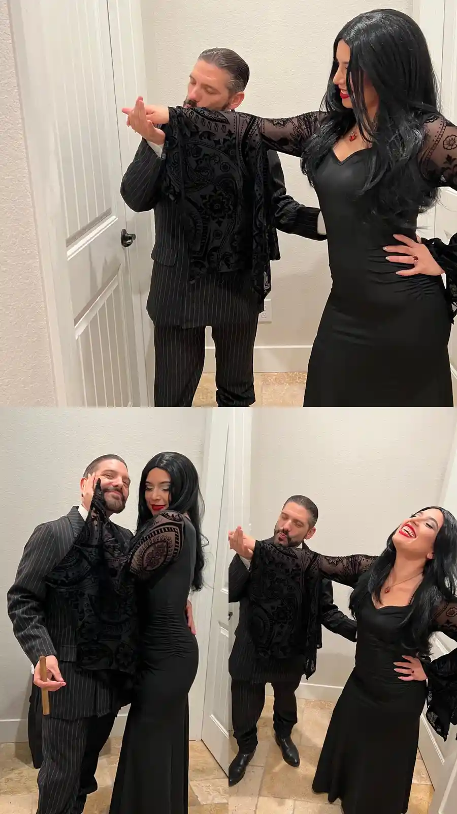 A man in a black pinstripe suit and a woman in a black dress with sheer lace sleeves are posing together in a hallway. In…