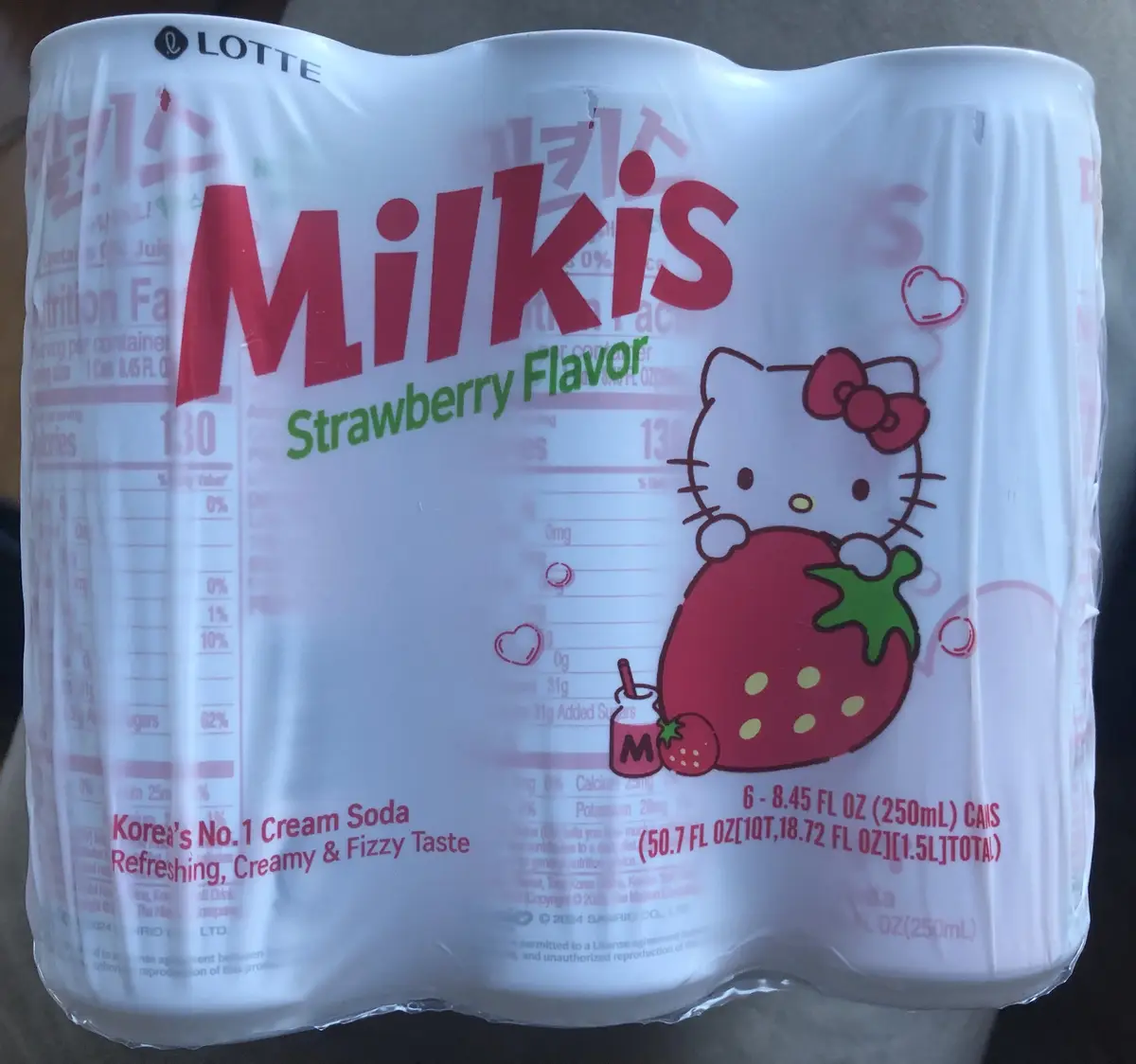 A close-up photo of a six-pack of Lotte Milkis Strawberry Flavor soda, featuring the Hello Kitty logo and character holding…