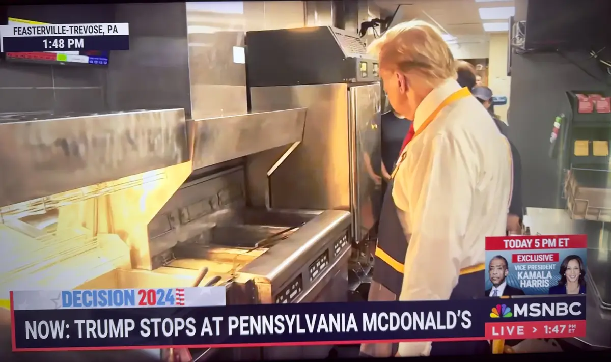 A news broadcast image shows a man with blond hair in a McDonald's kitchen, wearing a white shirt and dark apron with yellow…