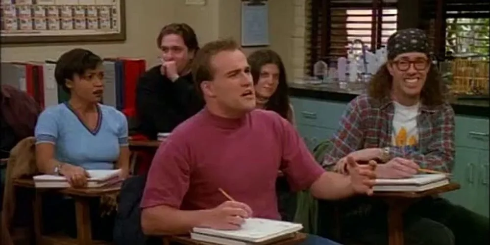 A still from the TV show 'Dawson's Creek' shows a classroom scene with several students. The central male student in a pink…
