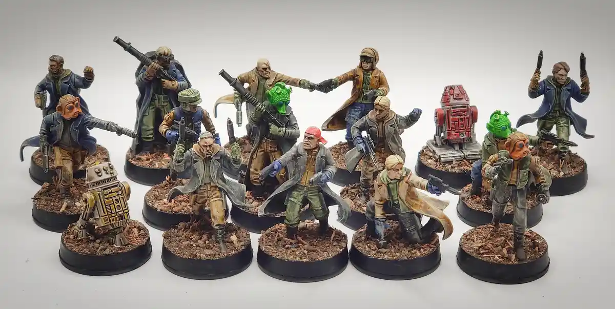 A collection of painted Star Wars miniatures, including human and alien characters and two R2-D2 droids, all posed with…