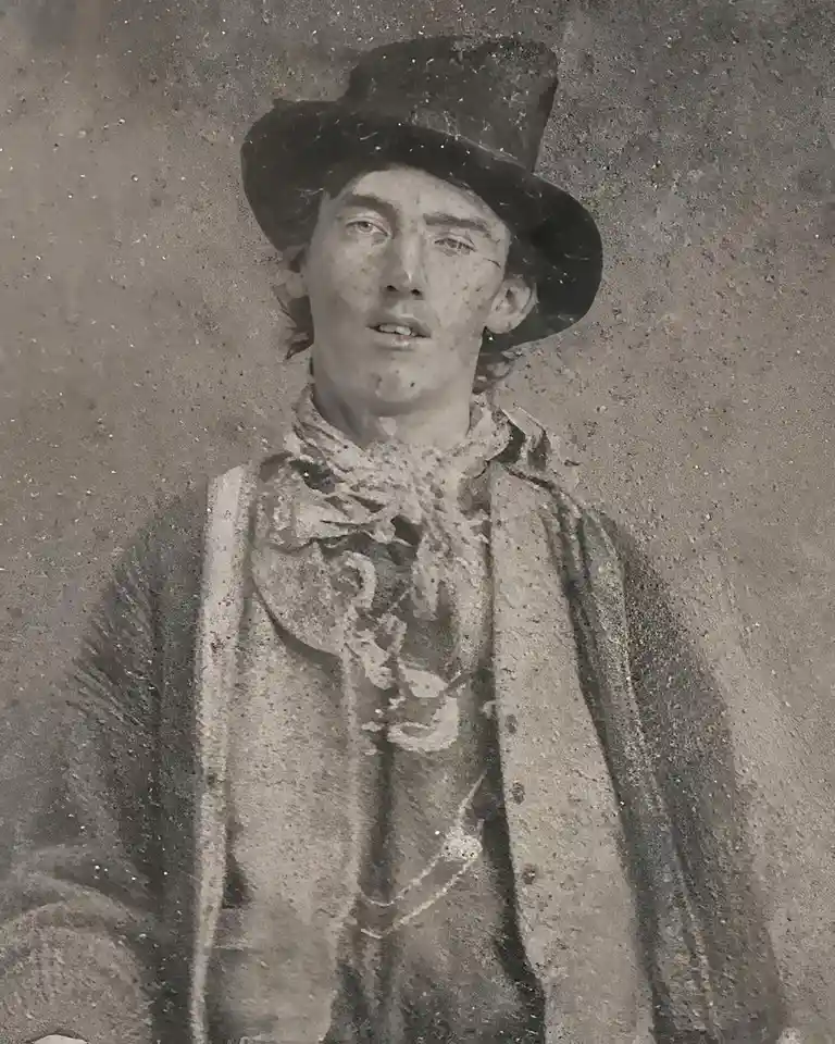 A sepia-toned, grainy, vintage-style portrait of a young man wearing a wide-brimmed hat and a patterned scarf, looking…
